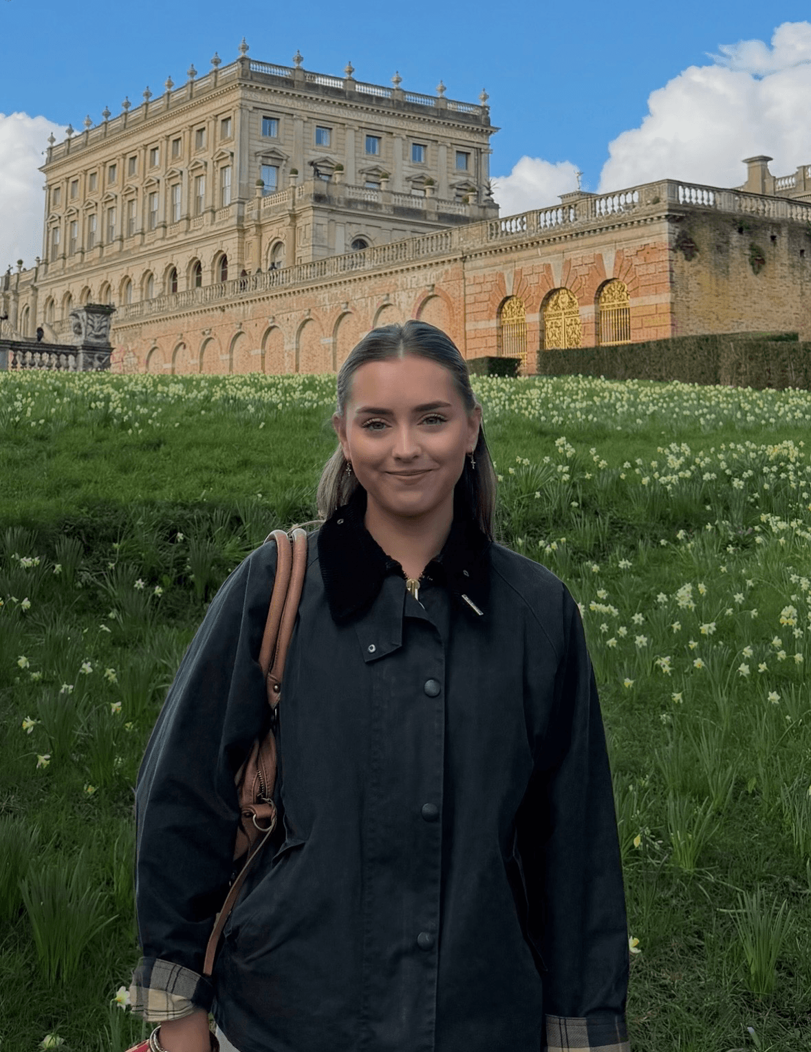 Madeline Humm standing in front of a historic house and flowered lawn